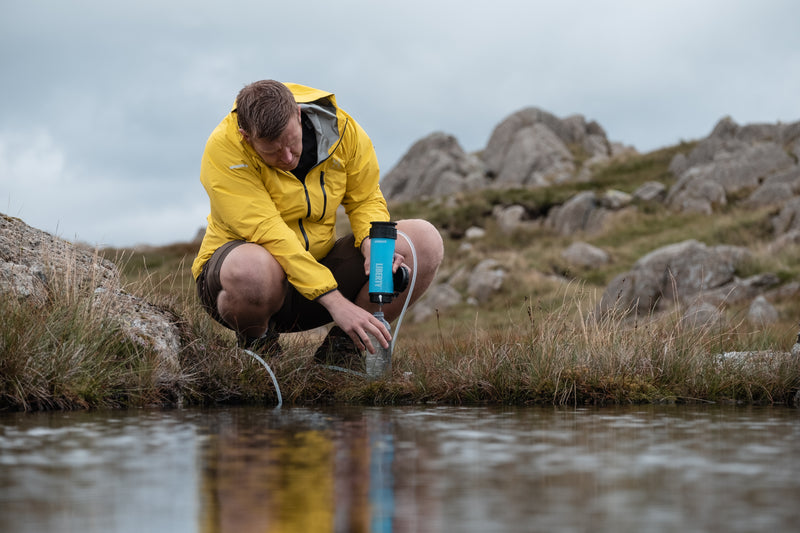 Carregar imagem no visualizador da galeria, A man purifying lake water using a LifeSaver Liberty bottle