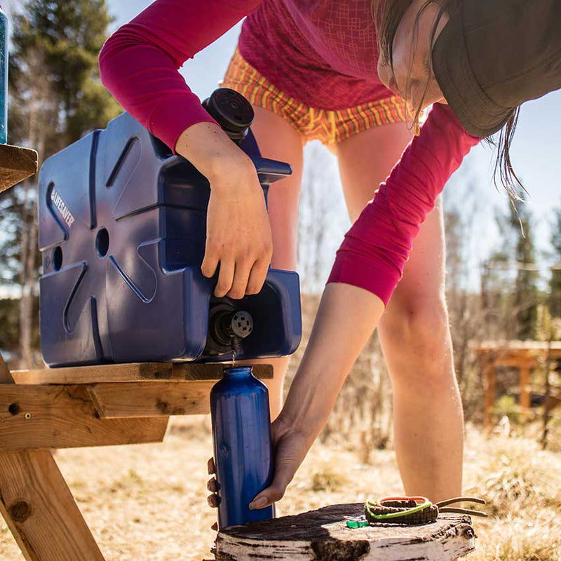 Carregar imagem no visualizador da galeria, Person camping using the LifeSaver water purification Jerrycan to fill a bottle of clean water
