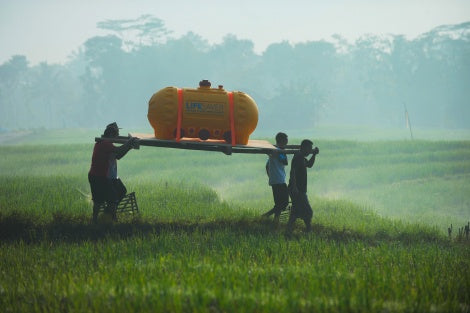 Men in Indonesia carrying a LifeSaver C2 across a meadow