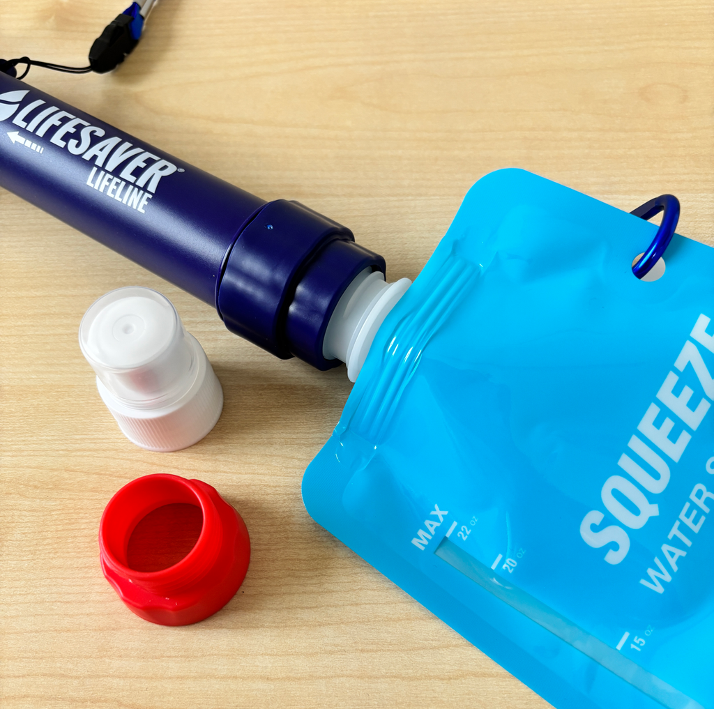 Lifesaver water filter with blue squeezable water pouch on a wooden surface